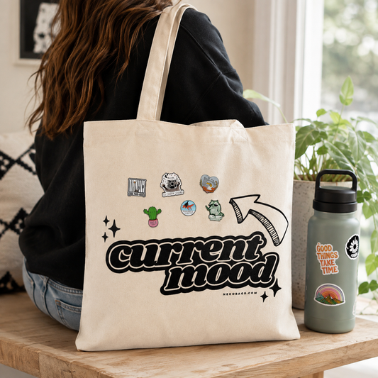 Woman carrying Current Mood customizable canvas tote with colorful enamel pins