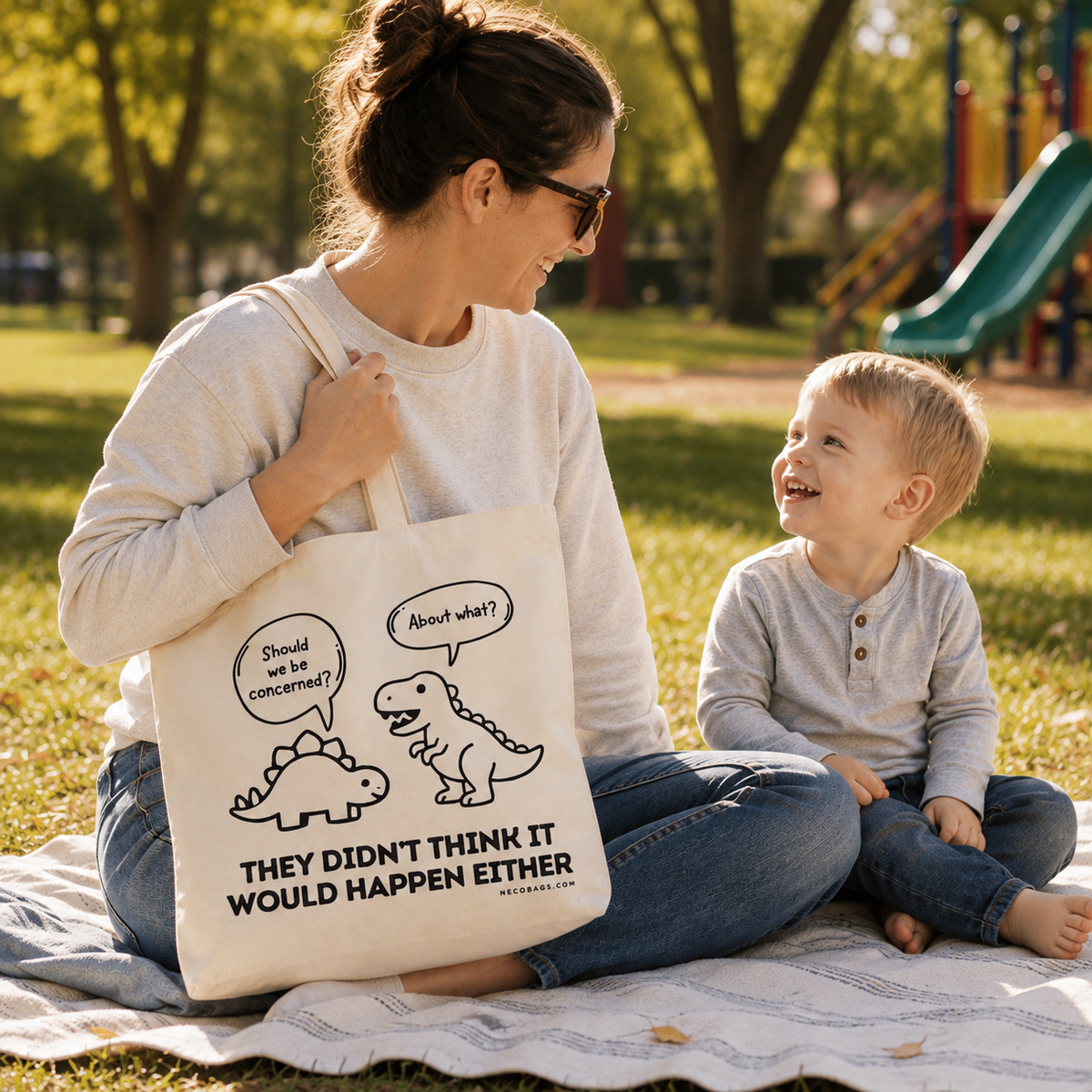 Woman carrying NECO dinosaur canvas tote bag at the park with child