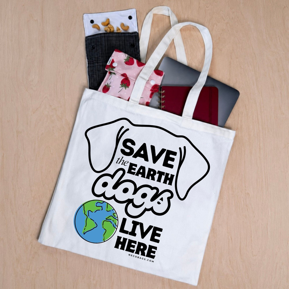 Natural cotton canvas tote bag with Save the Earth Dogs Live Here dog lover graphic featuring dog ears and a colorful Earth with items shown coming out of the bag