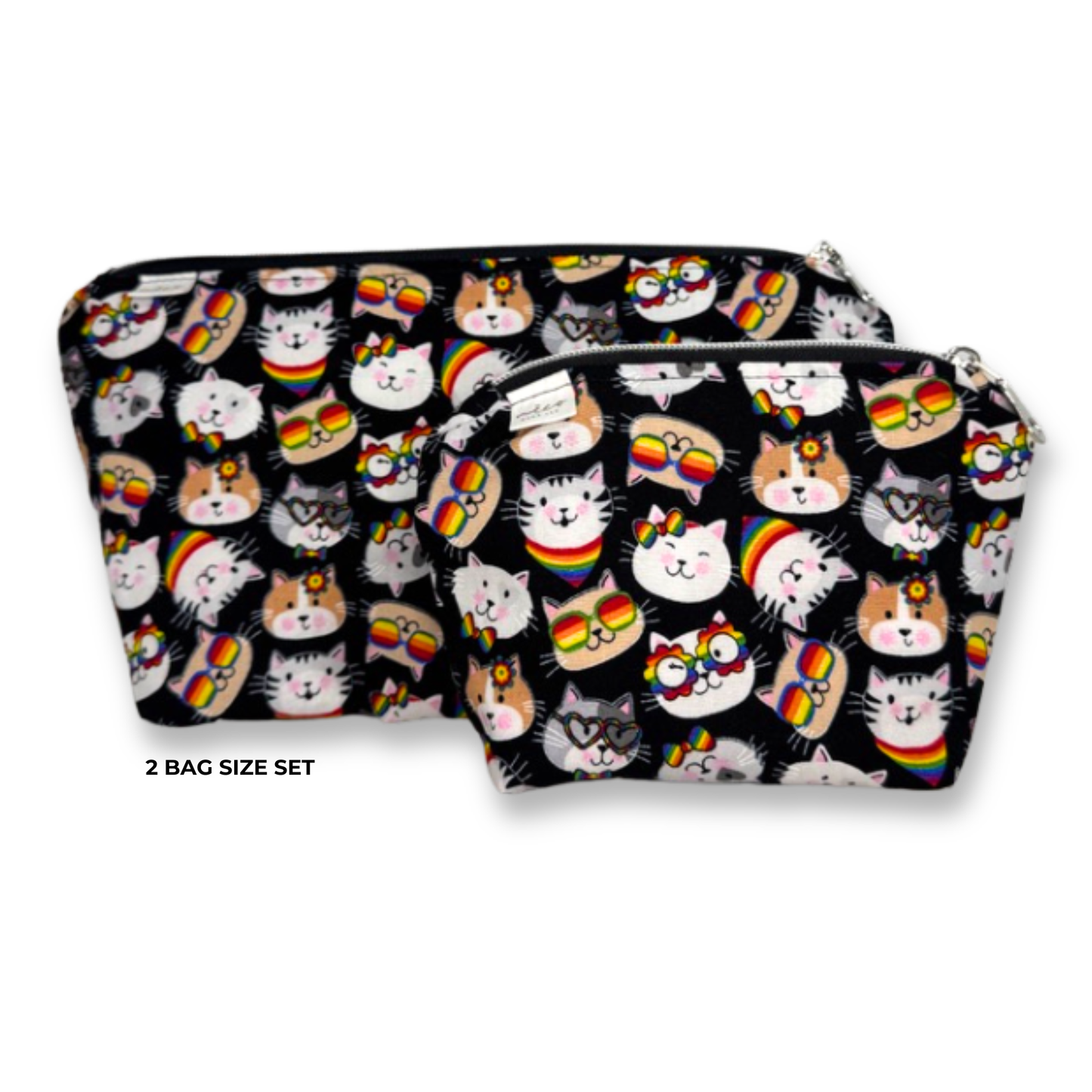 Two zippered cosmetic pouches in a size set, featuring a black background covered in a colorful cartoon cat print with rainbow accents. The text '2 BAG SIZE SET' is printed below the larger pouch on a white background. Machine Washable Cosmetic Bags