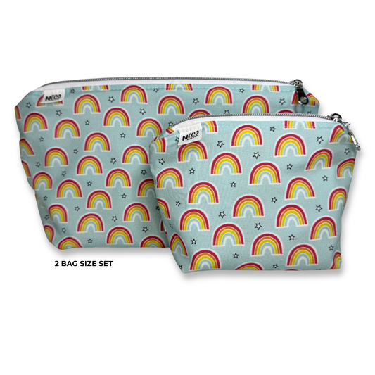 Two zippered pouches in a matching set, featuring a light blue background with a repeating rainbow and star pattern. The larger pouch is positioned behind the smaller one, with the text '2 BAG SIZE SET' printed below on a white background. Machine washable cosmetic bags.