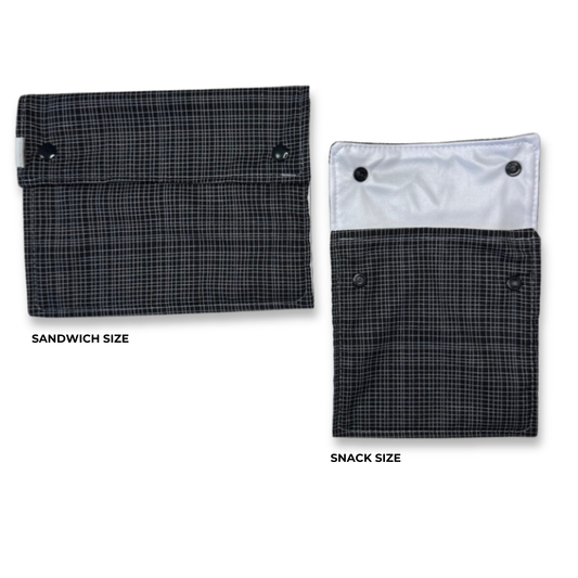 Two fabric pouches shown on a white background, labeled Sandwich Size and Snack Size. Both have a dark gray and black plaid exterior, with one showing a black snap closure and the other showing a black snap closure over a white interior lining. Machine Washable snack and sandwich bags