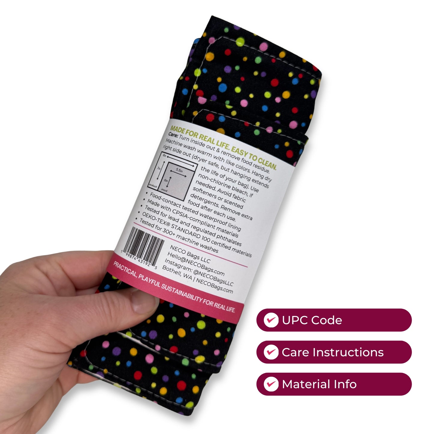 A hand holds a folded black fabric item with multicolored polka dots and a white paper label showing product information. A bundled set of cute reusable snack and sandwich bags