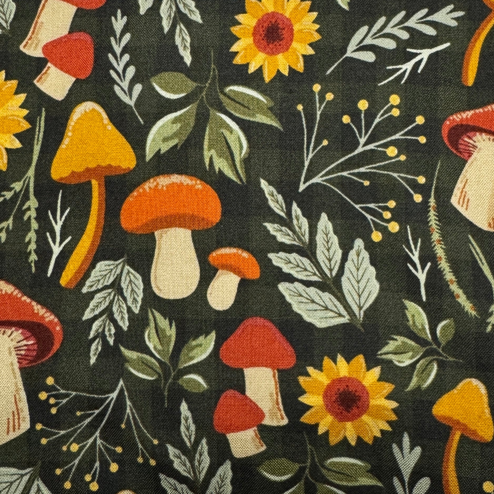 A close-up of a fabric pattern featuring a woodland theme with orange and red mushrooms, yellow sunflowers, green leaves, and delicate white botanical stems on a dark charcoal background.