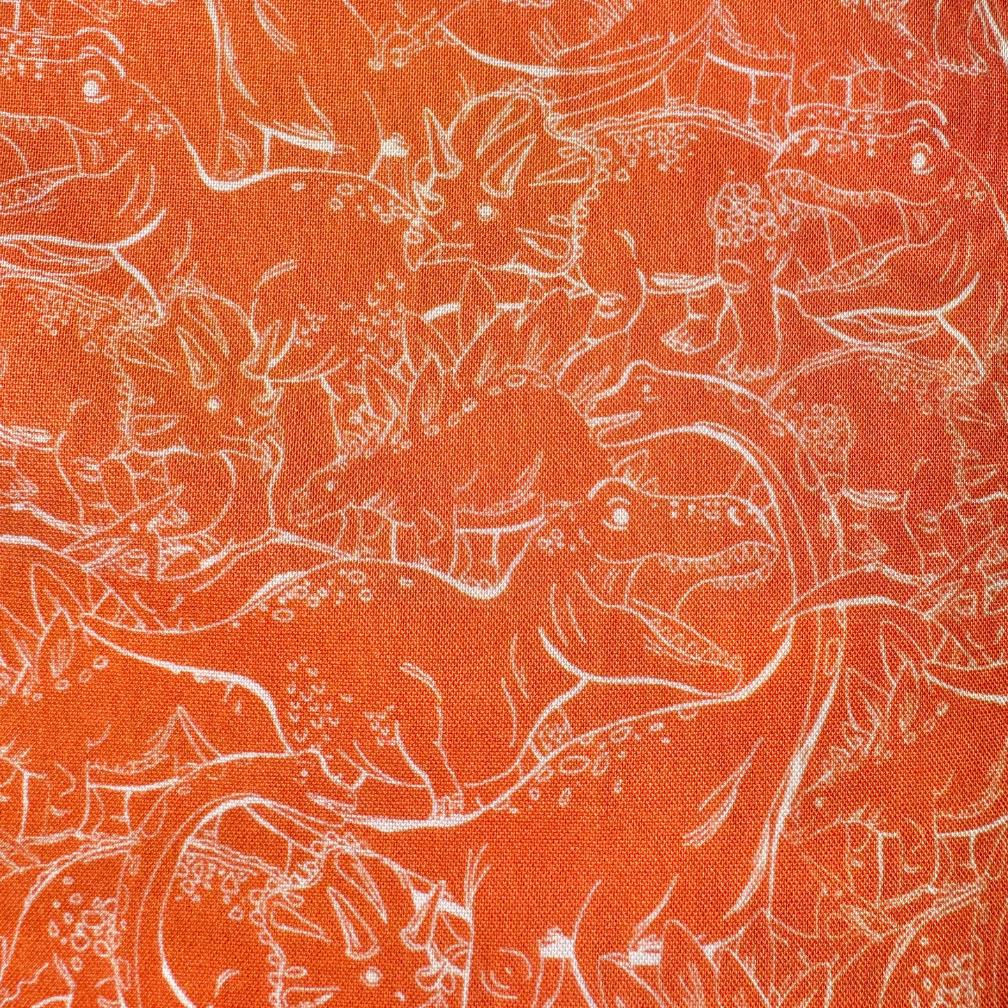 Orange fabric with a white line-art pattern of dinosaurs and prehistoric animals filling the frame.