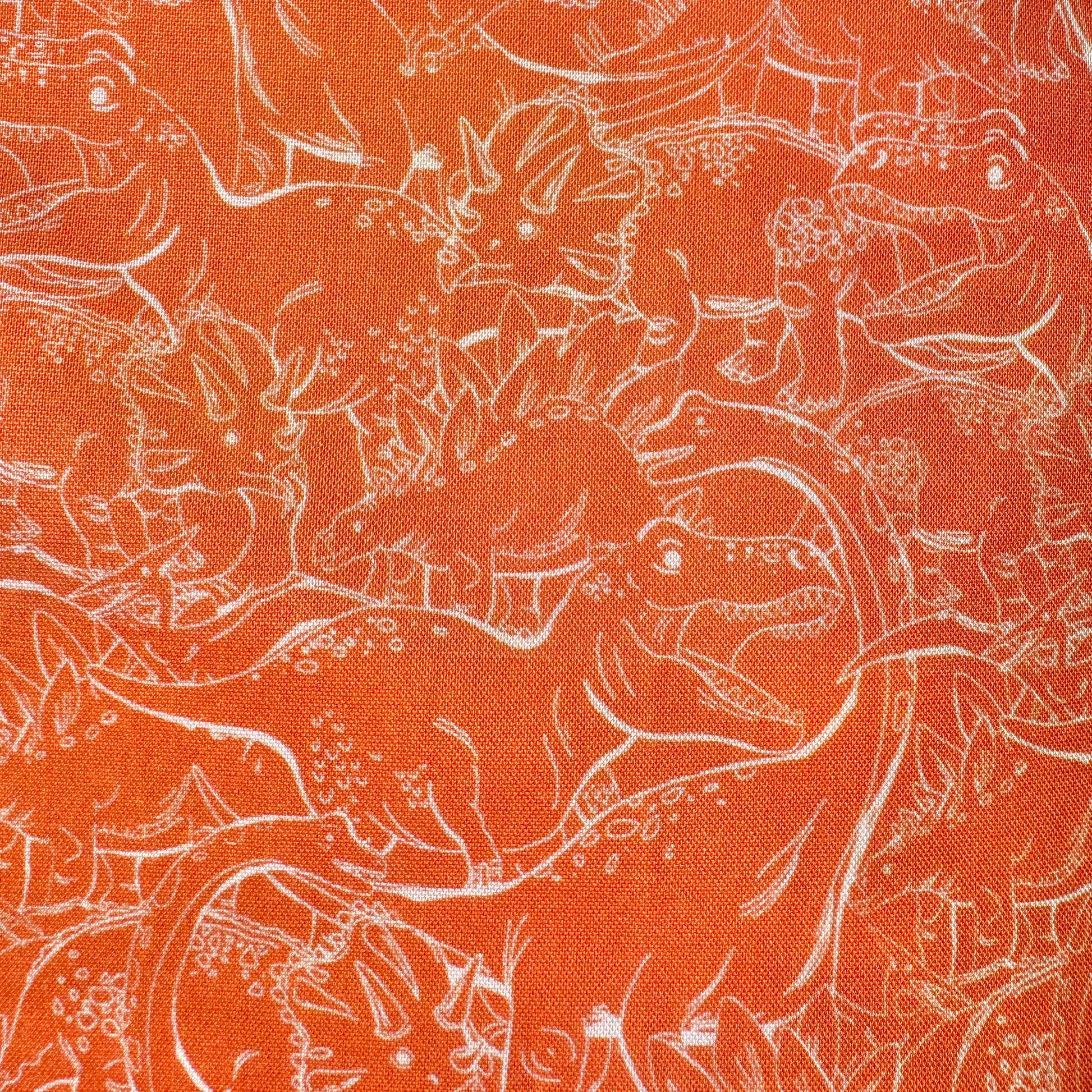 Orange fabric with a white line-art pattern of dinosaurs and prehistoric animals filling the frame.
