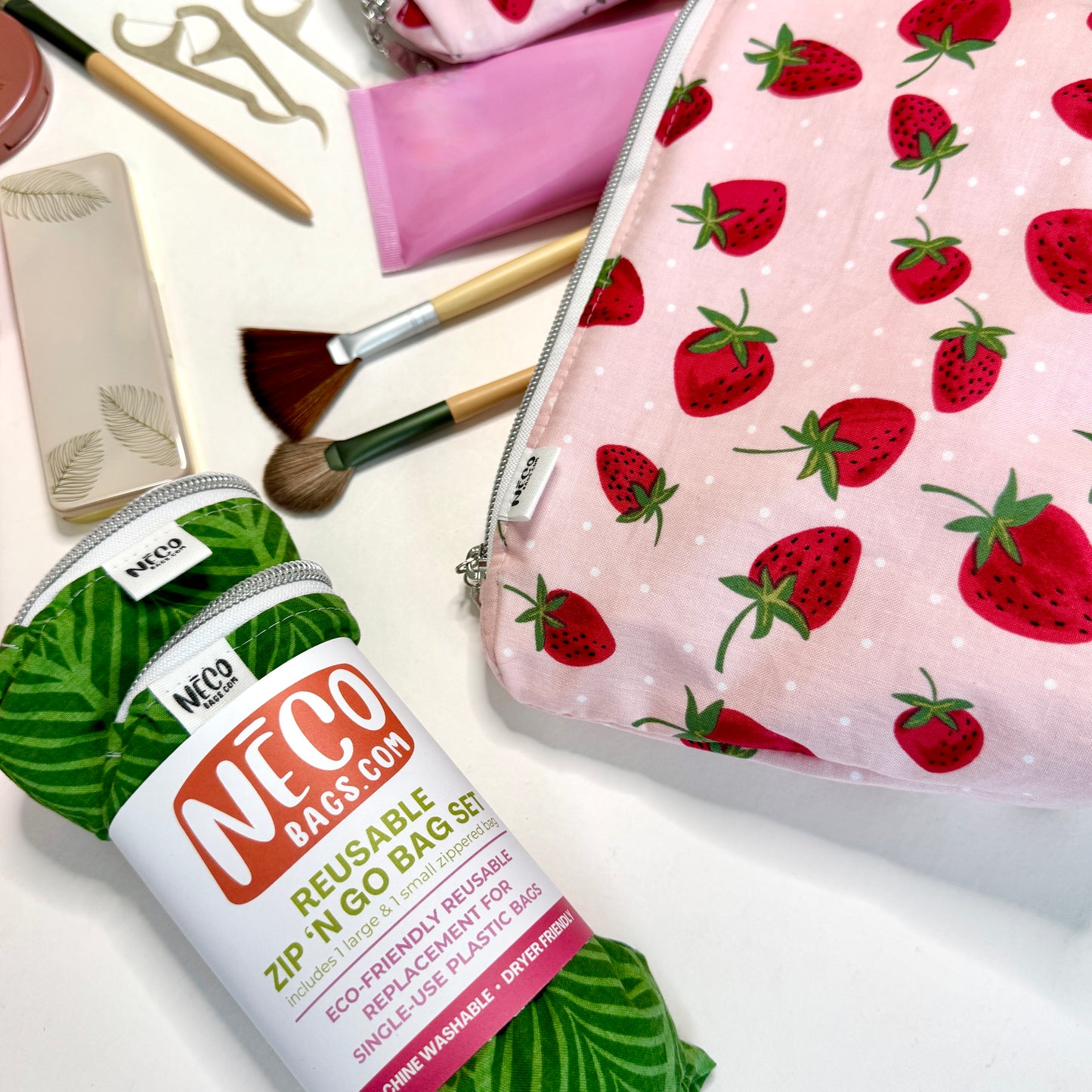 NECO reusable zip 'N'GO bag set shown in a styled flat-lay with makeup accessories on a white surface. Machine washable cosmetic bags