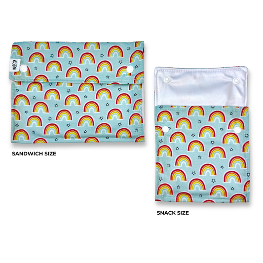 Two reusable cloth washable reusable food bags. Snack and sandiwich bags with fun  rainbow fabric pattern. repeating rainbow and star print on a light blue background, shown on a white background. The left pouch is labeled SANDWICH SIZE and the right pouch is labeled SNACK SIZE.cute 