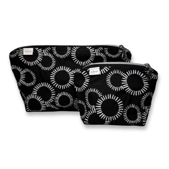 Two black makeup bags with white circular pattern on a white background