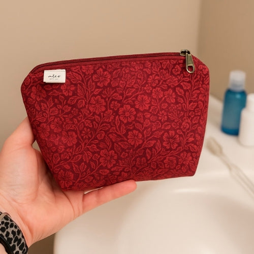 Red floral-patterned pouch held in a hand with a neutral background