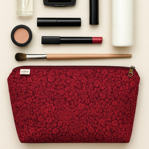 Makeup items including a red floral pouch on a light background